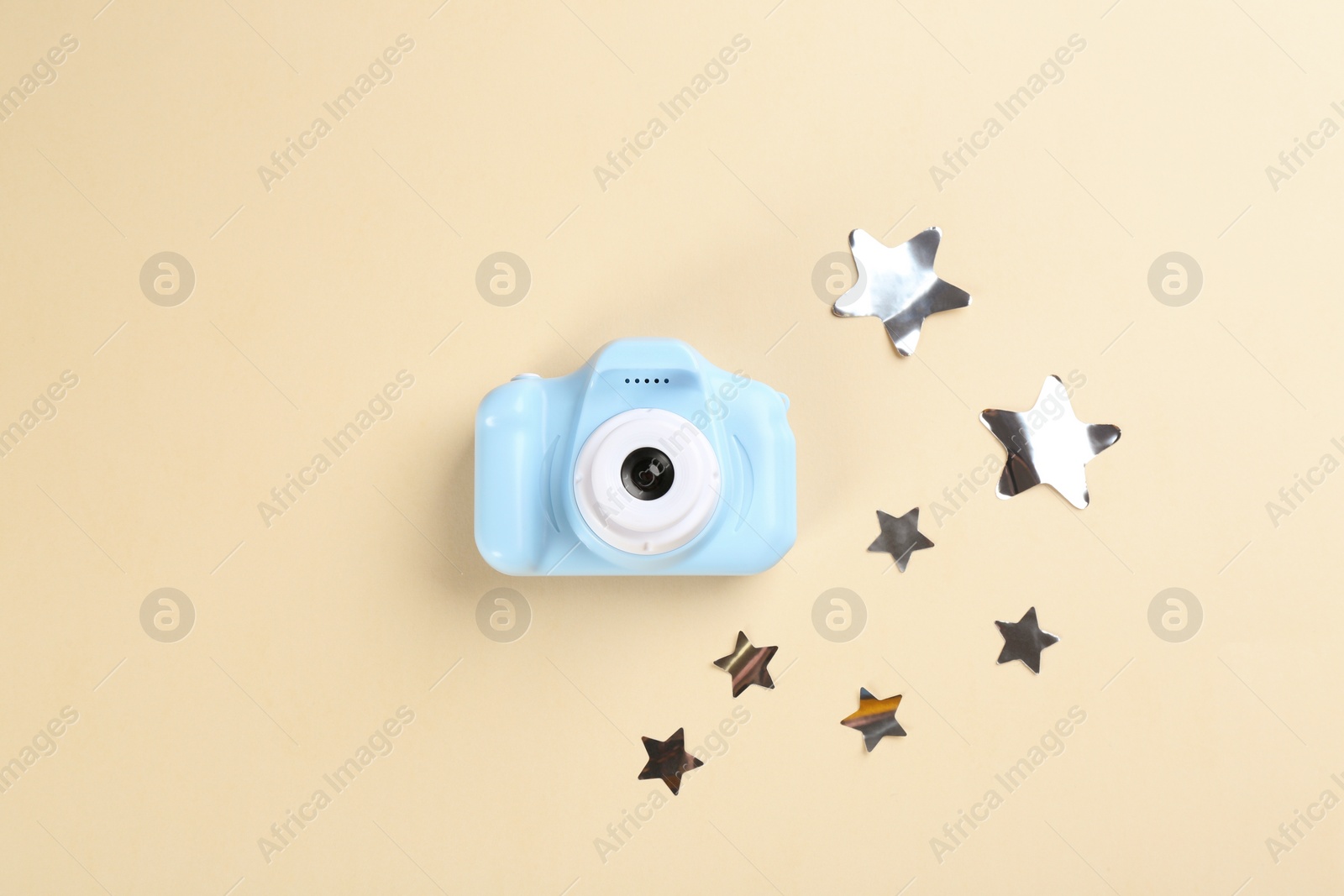 Photo of Toy camera and stars on beige background, flat lay