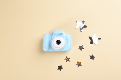 Toy camera and stars on beige background, flat lay