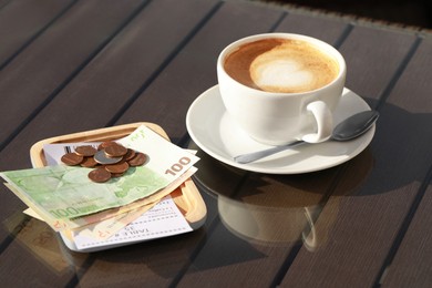 Photo of Tasty hot coffee and payment for order on table. Leave tip