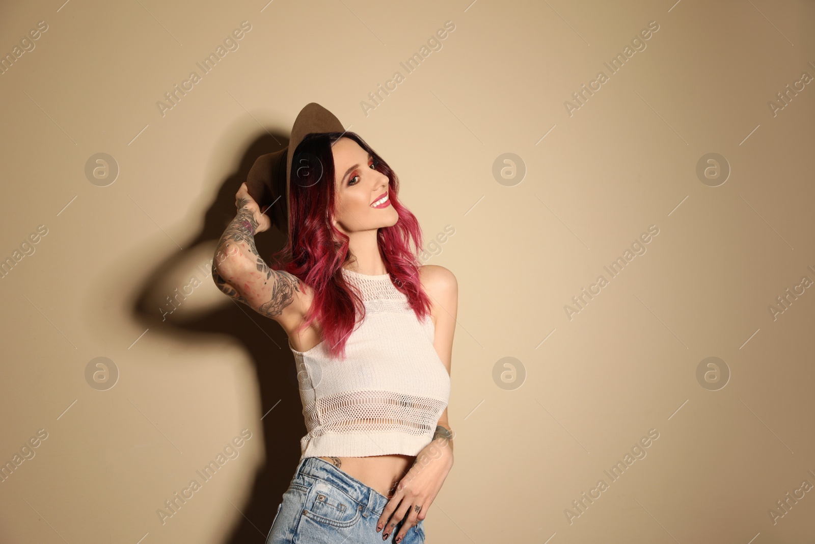 Photo of Beautiful woman with tattoos on body against beige background. Space for text