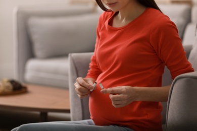 Photo of Young pregnant woman breaking cigarette at home, closeup. Space for text