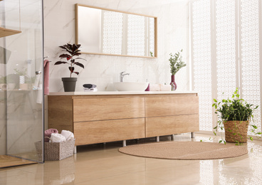 Photo of Stylish bathroom interior with countertop, mirror and plants. Design idea