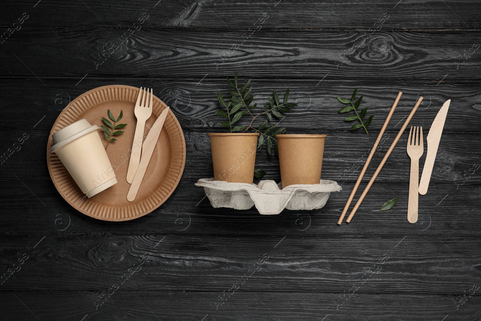 Photo of Flat lay composition with disposable tableware and green twigs on black wooden background