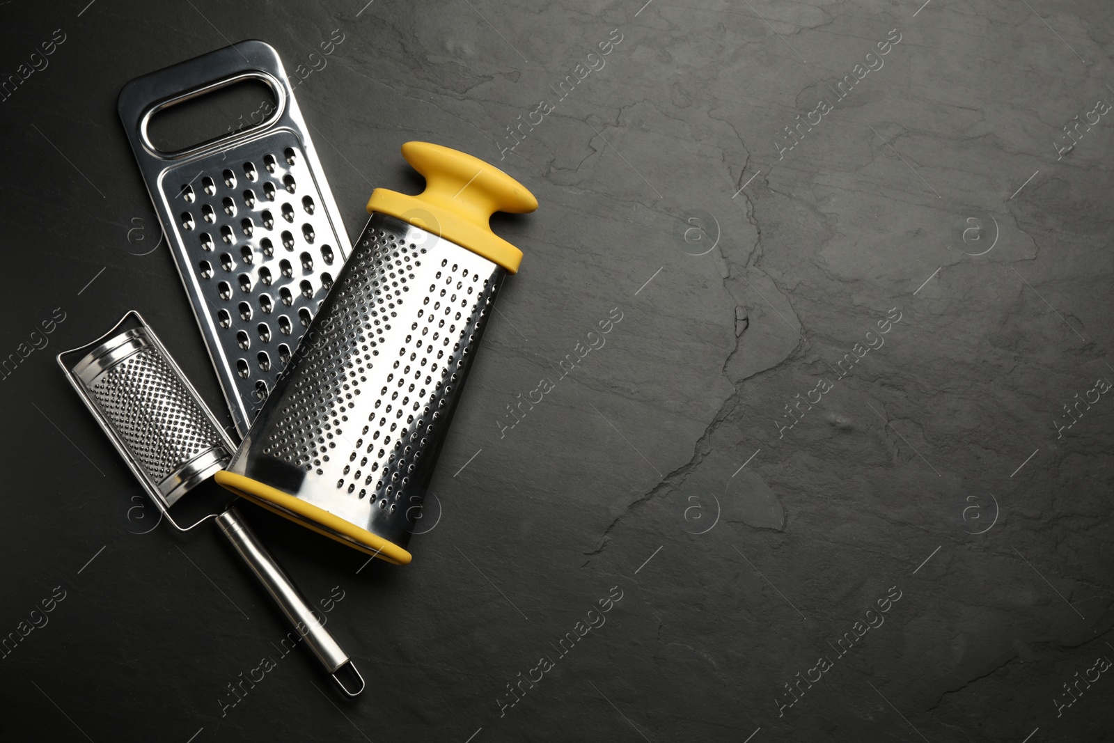 Photo of Different modern graters on black table, flat lay. Space for text