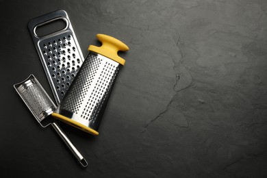 Photo of Different modern graters on black table, flat lay. Space for text