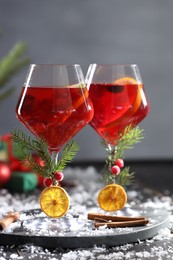 Photo of Christmas Sangria cocktail in glasses and snow on dark wooden table
