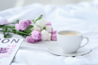 Cup of coffee, beautiful flowers and magazine on fabric