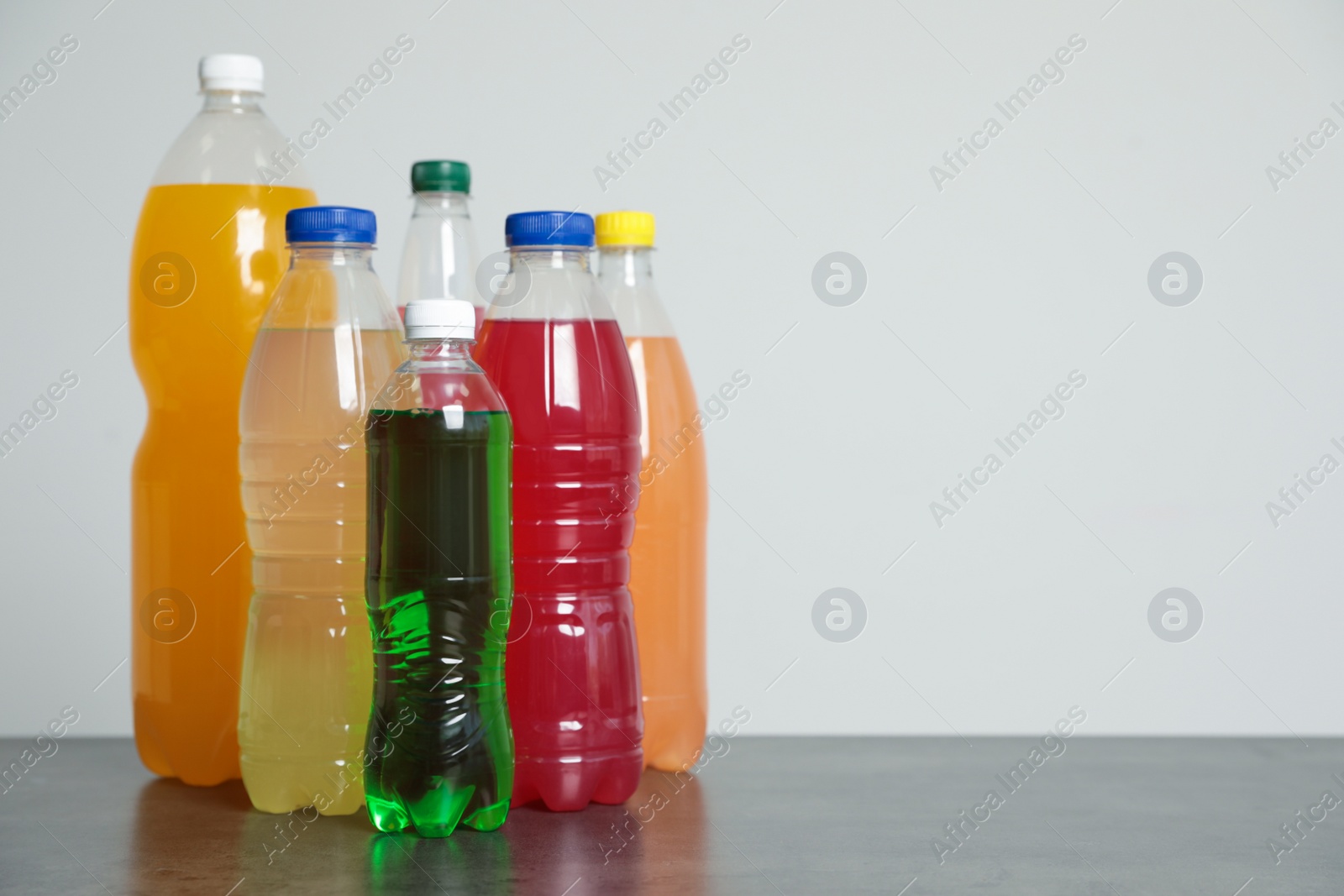 Photo of Bottles of soft drinks on table against grey background. Space for text