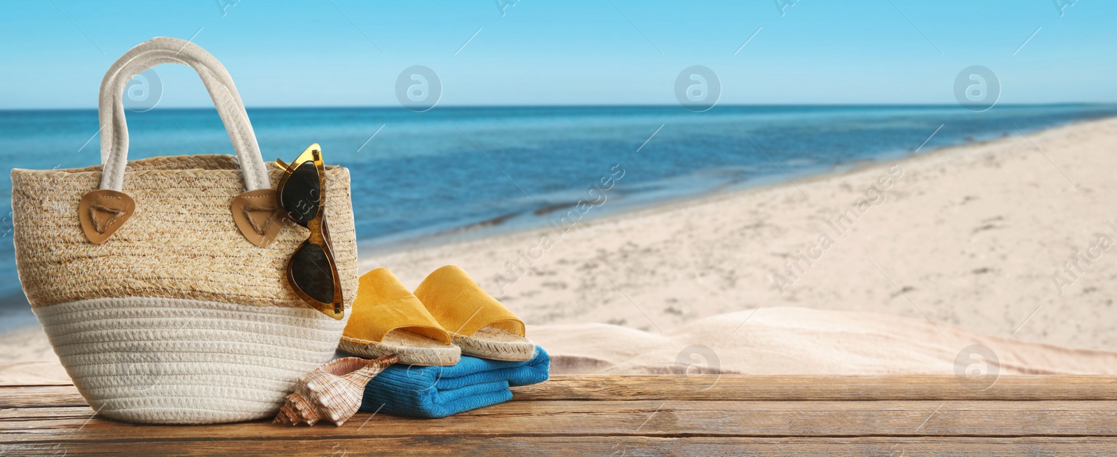 Image of Beach accessories on wooden surface near sea, space for text. Banner design 