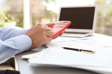 Photo of Tax accountant working with calculator at table