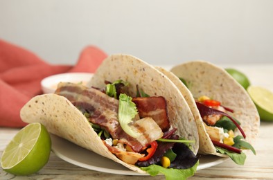 Photo of Delicious tacos with fried bacon and lime on white wooden table, closeup