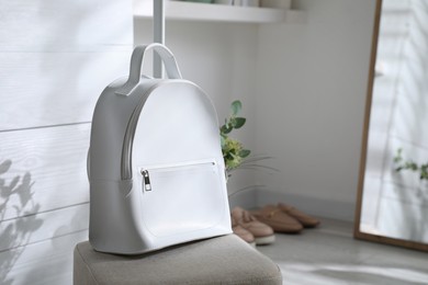 Stylish backpack on pouf in dressing room