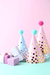 Party hats and gift boxes on color background