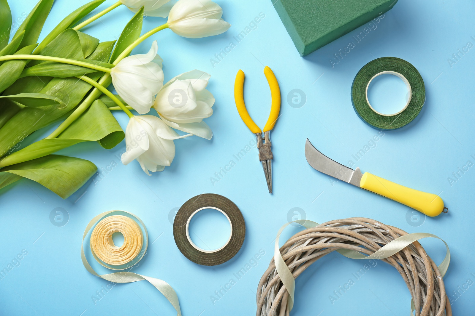 Photo of Florist equipment with flowers on color background, top view