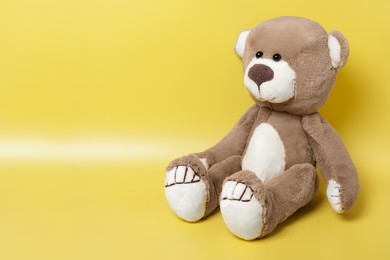 Photo of Cute teddy bear on yellow background, space for text
