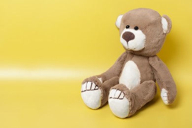 Cute teddy bear on yellow background, space for text