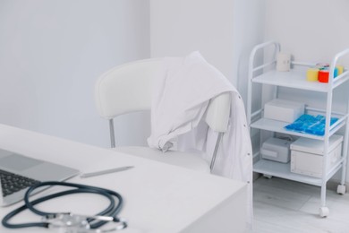 White doctor's gown hanging on chair in clinic
