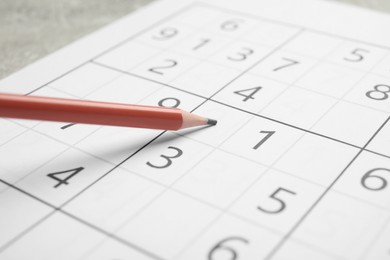 Photo of Sudoku and pencil on grey table, closeup