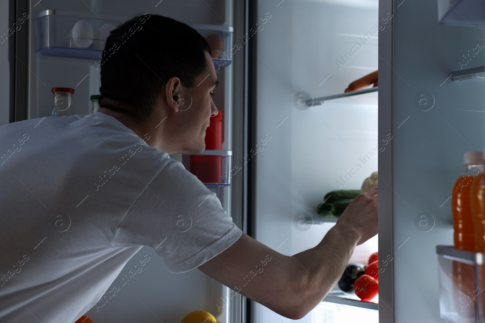 Photo of Man near refrigerator in kitchen at night