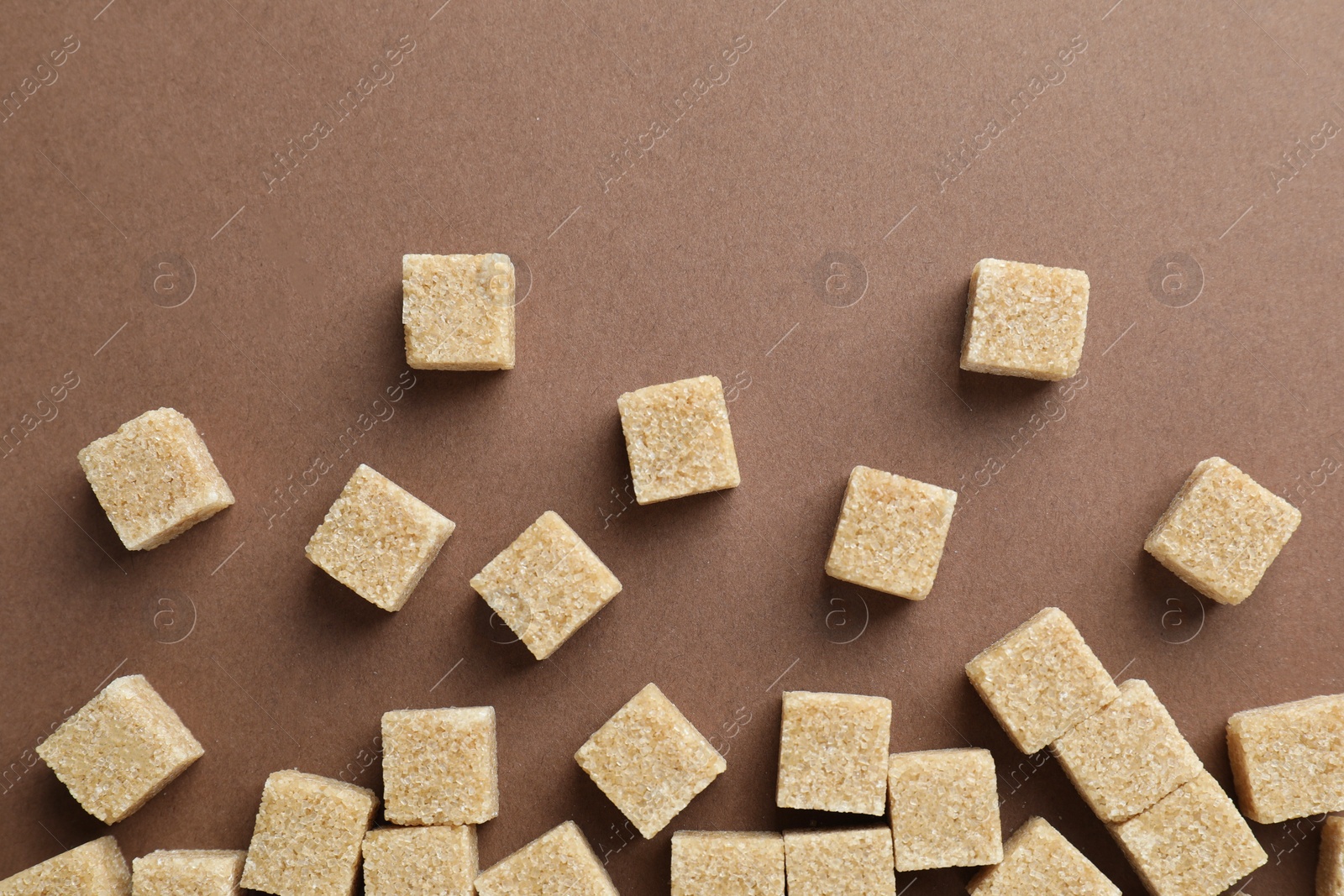 Photo of Brown sugar cubes on color background, top view