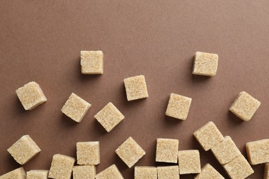 Brown sugar cubes on color background, top view