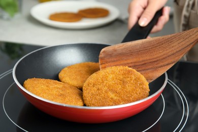 Woman cooking breaded cutlets in frying pan on stove, closeup