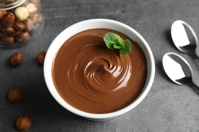 Photo of Ceramic bowl with sweet chocolate cream and mint on table, view from above