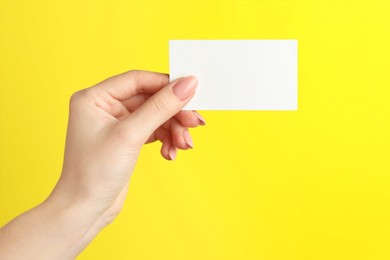 Photo of Woman holding blank business card on yellow background, closeup. Mockup for design