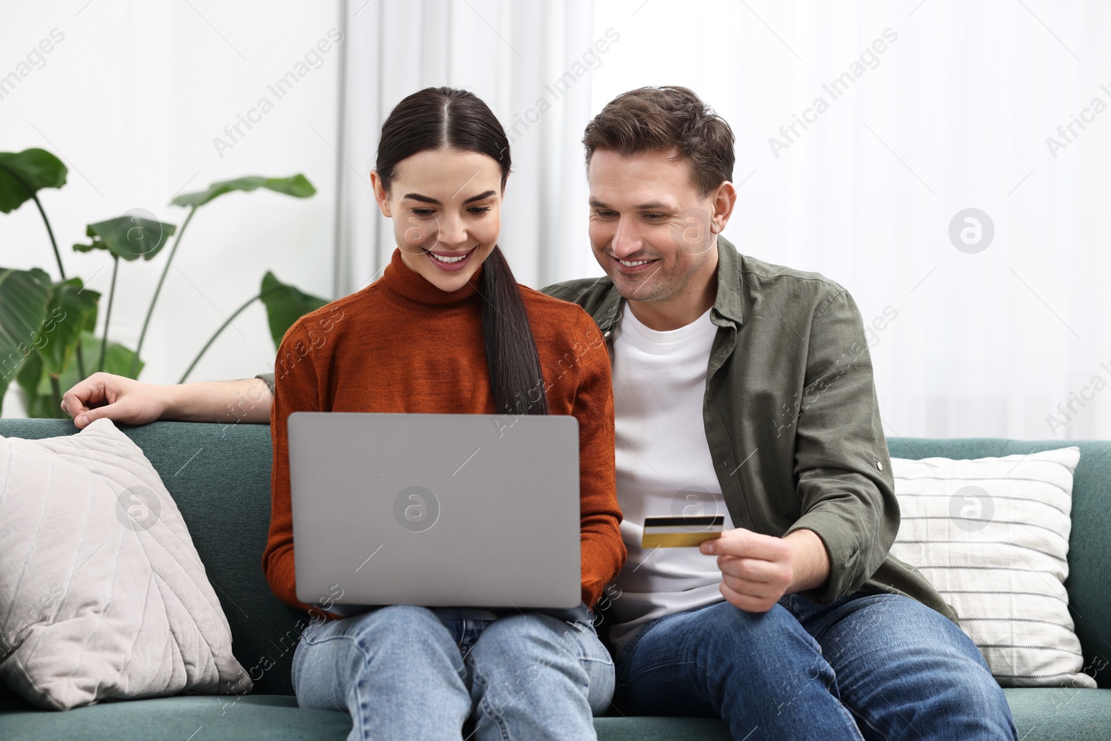 Photo of Happy couple with laptop and credit card shopping online together at home