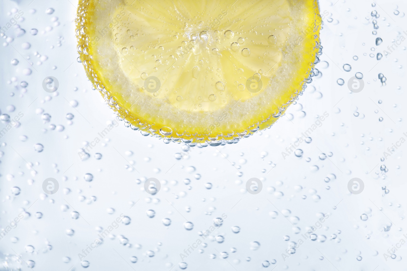 Photo of Juicy lemon slice in soda water, closeup