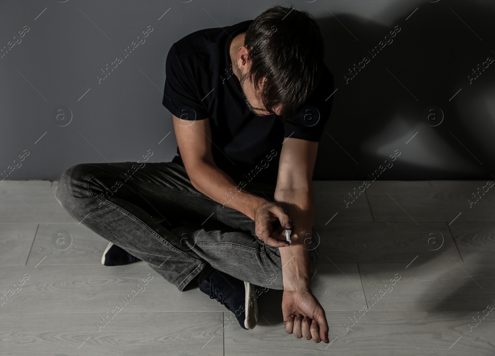 Photo of Male drug addict making injection near grey wall