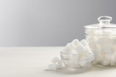 Photo of Glass jar and bowl with white sugar cubes on table, space for text