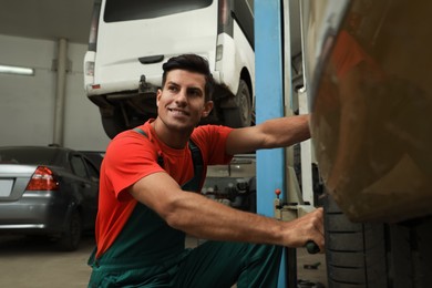 Professional mechanic changing wheel at automobile repair shop