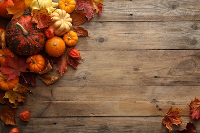 Photo of Dry autumn leaves and pumpkins on wooden table, flat lay. Space for text