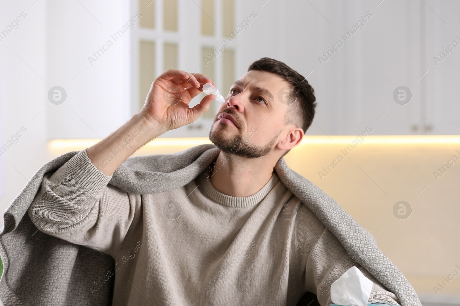 Photo of Ill man using nasal drops at home