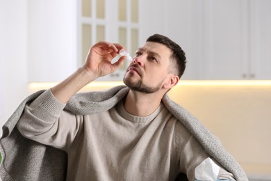 Photo of Ill man using nasal drops at home