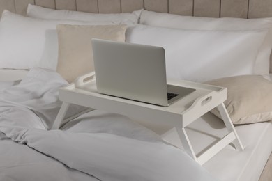 Photo of White tray table with laptop on bed