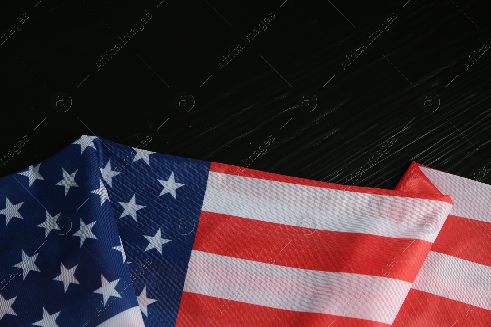 Photo of Flag of USA on black wooden table, top view. Space for text