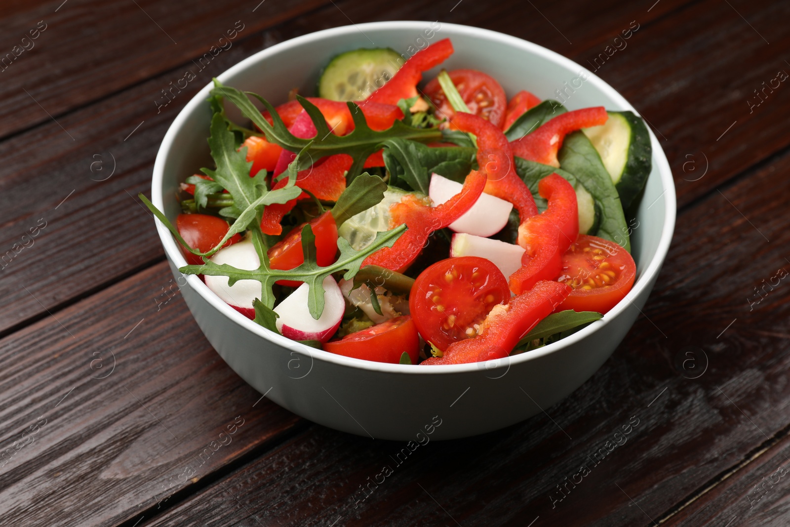 Photo of Tasty fresh vegetarian salad on dark wooden table