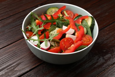 Photo of Tasty fresh vegetarian salad on dark wooden table