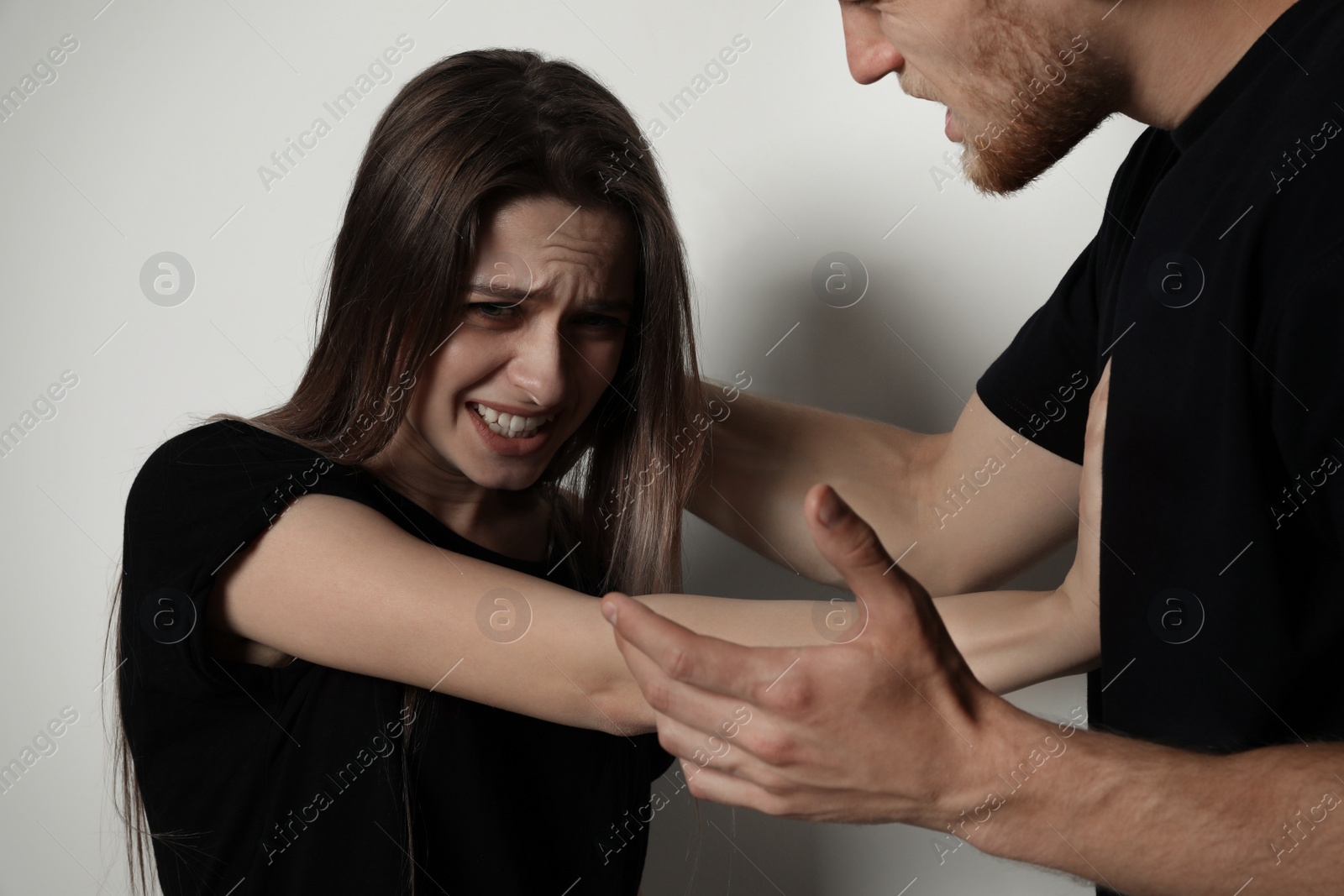 Photo of Man fighting with woman on light background. Stop sexual assault