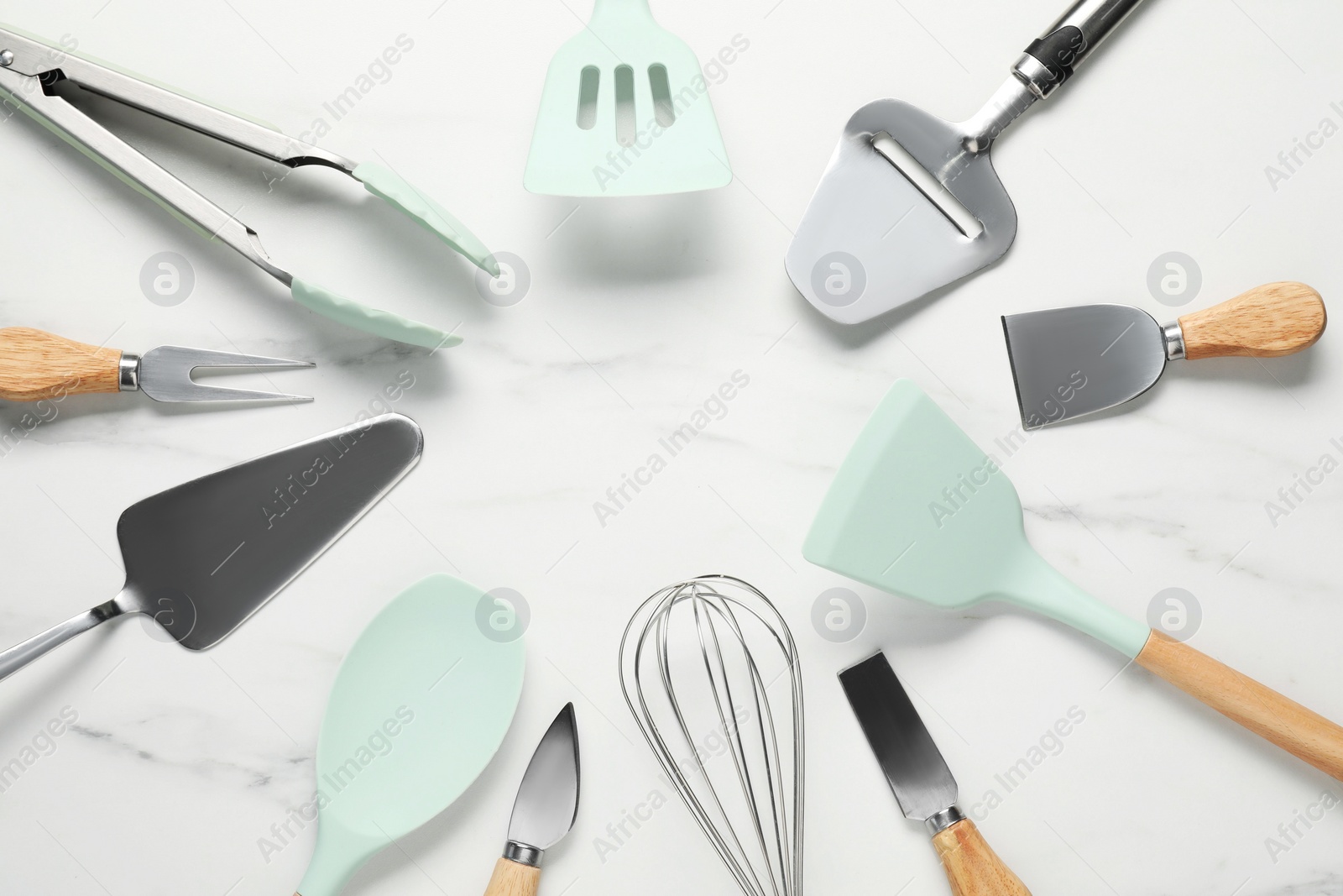 Photo of Frame of different spatulas and other kitchen utensils on light marble table, flat lay. Space for text