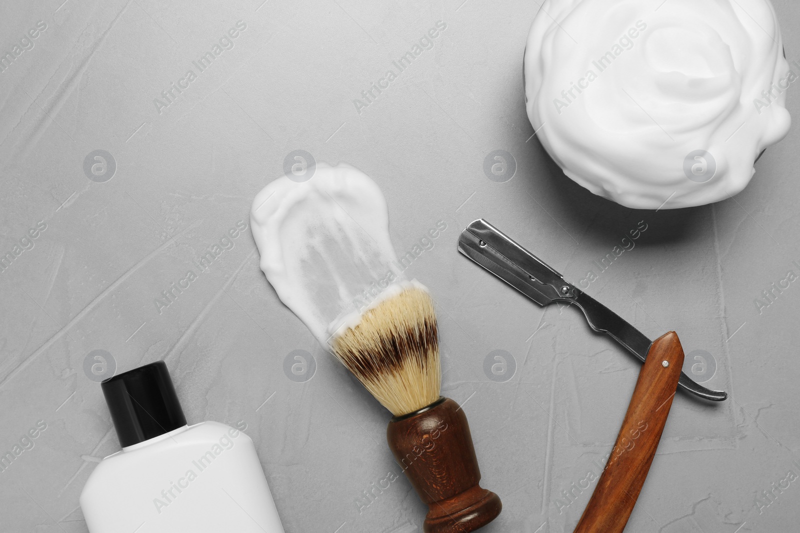 Photo of Set of men's shaving tools and foam on light gray textured table, flat lay