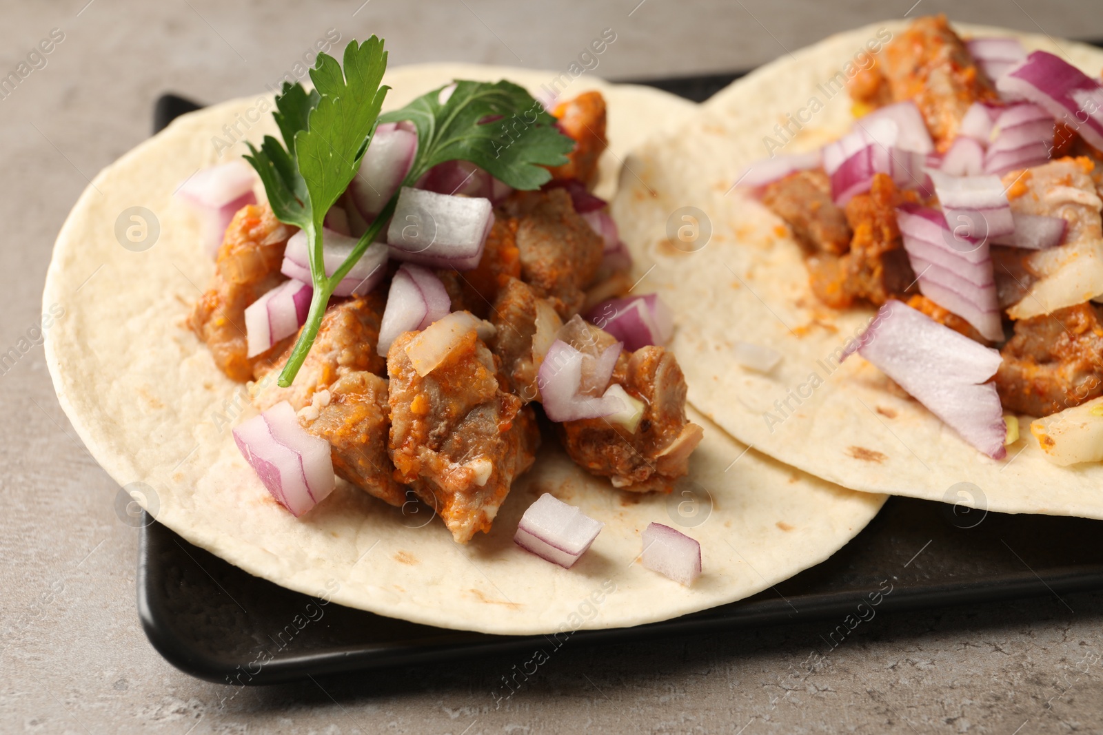 Photo of Delicious tacos with vegetables and meat on grey textured table, closeup