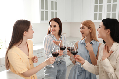 Photo of Beautiful young ladies with wine in kitchen. Women's Day