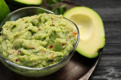 Photo of Glass bowl with delicious guacamole and fresh avocado on table, closeup. Space for text