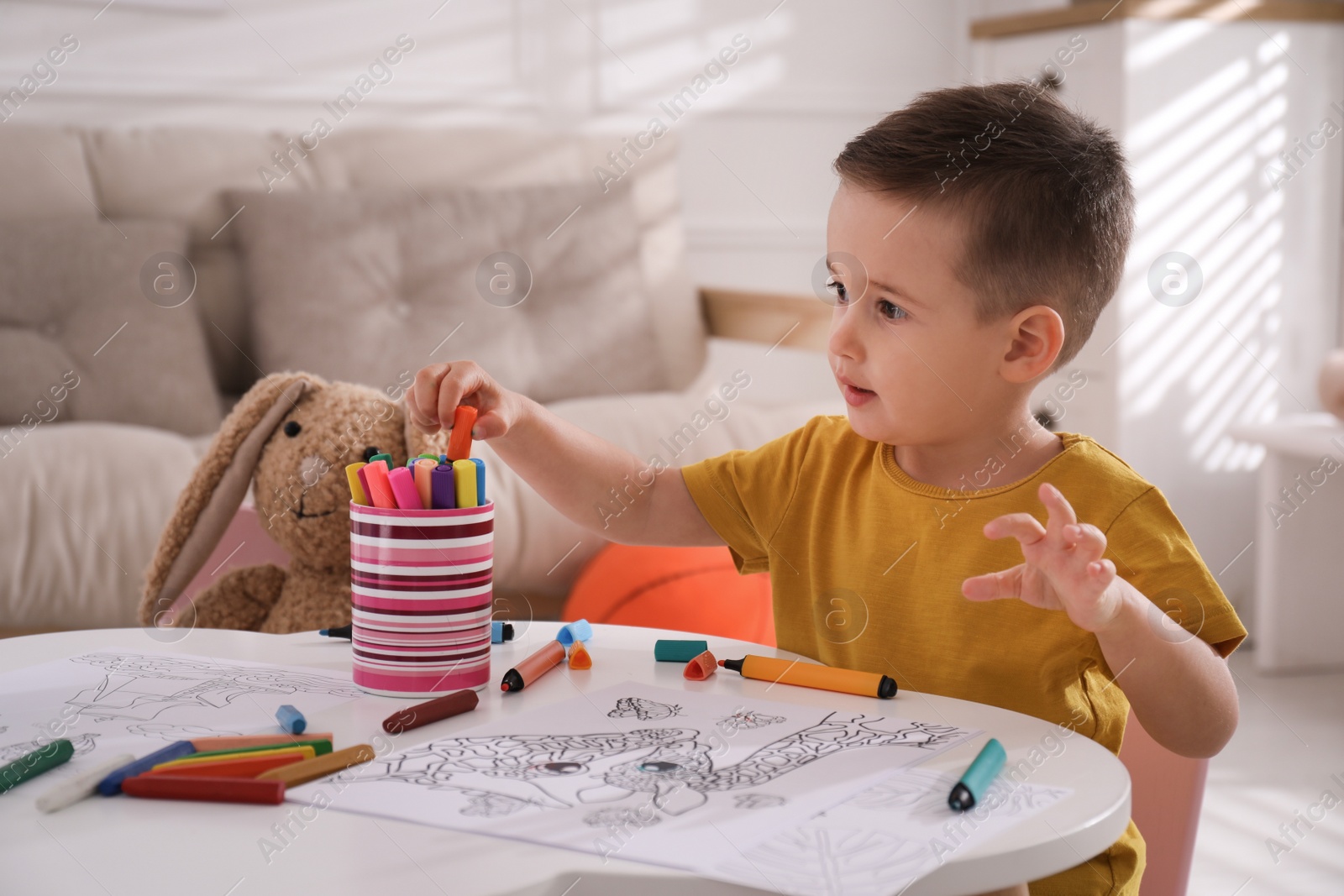 Photo of Cute child coloring drawing at table in room