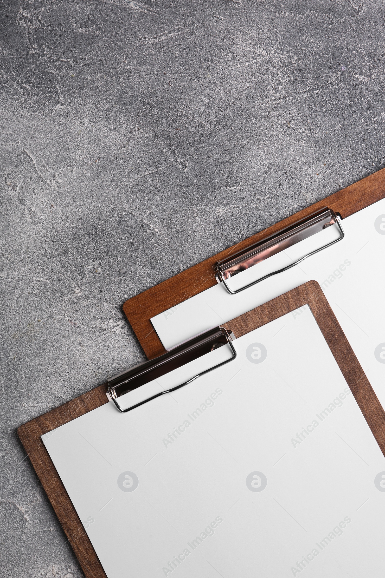 Photo of New wooden clipboards with sheets of blank paper on grey textured table, flat lay. Space for text