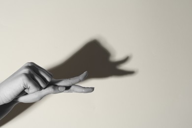 Shadow puppet. Woman making hand gesture like snail on light background, closeup with space for text. Black and white effect