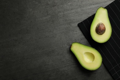 Halves of delicious ripe avocado on grey grey table, flat lay. Space for text